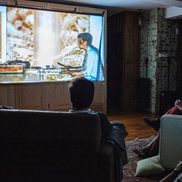 A group of people watch Filipa César’s film Spell Reel on a projector screen.